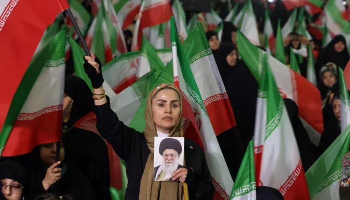 Foto: Mulher iraniana acena com a bandeira nacional do Irã enquanto segura uma f